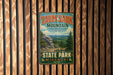 A vintage metal sign for Taun sauk Mountain, the highest point in Missouri, is displayed on a wooden wall.
