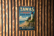 A vintage metal sign for Tawas Point State Park in Michigan, featuring a lighthouse and a beach scene.