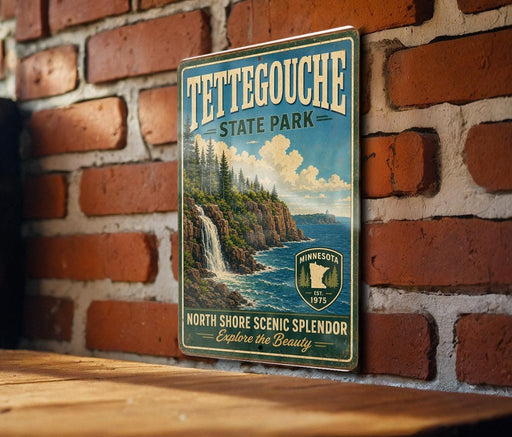A vintage-style metal sign for Tettegouche State Park, featuring a scenic landscape with a waterfall and mountains, mounted on a brick wall.