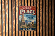A vintage-style metal sign that reads "This is the PLACE Heritage Park" and "UTAH" is displayed on a wooden wall.