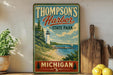 A vintage-style sign for "Thomson's Harbor State Park" in Michigan, featuring a lighthouse and a scenic coastal landscape.