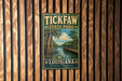 A vintage metal sign for Tickfaw State Park in Louisiana, featuring a scenic illustration of a bayou landscape with a wooden walkway and a bridge.
