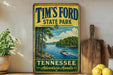 A vintage-style sign for Tim's Ford State Park in Tennessee, featuring a scenic image of a lake with a boat and trees.