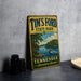 A vintage-style metal sign for Tim's Ford State Park in Tennessee, featuring a scenic lake and boat illustration, is displayed on a gray countertop.