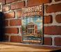 A vintage-style metal sign for Tombstone Courthouse, a historic park in Arizona, with a brick wall in the background.