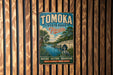A vintage metal sign for Tomoka State Park, Florida, featuring a scenic illustration of a bridge, palm trees, and a heron in the water.