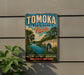 A vintage-style metal sign for Tomoka State Park in Florida, featuring a scenic illustration of a bridge, palm trees, and a bird.