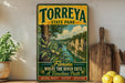 A vintage-style sign for Torreya State Park, featuring a scenic illustration of a river surrounded by lush greenery.