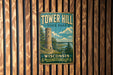 A vintage-style metal sign for Tower Hill State Park in Wisconsin, featuring a tower and a scenic landscape.