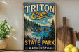 A vintage-style sign for Triton Cove State Park in Washington, featuring a scenic coastal landscape with pine trees, a rocky cliff, and a beach.