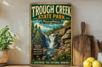 A vintage-style sign for the Trough Creek State Park in Pennsylvania, featuring a scenic illustration of a waterfall surrounded by nature.