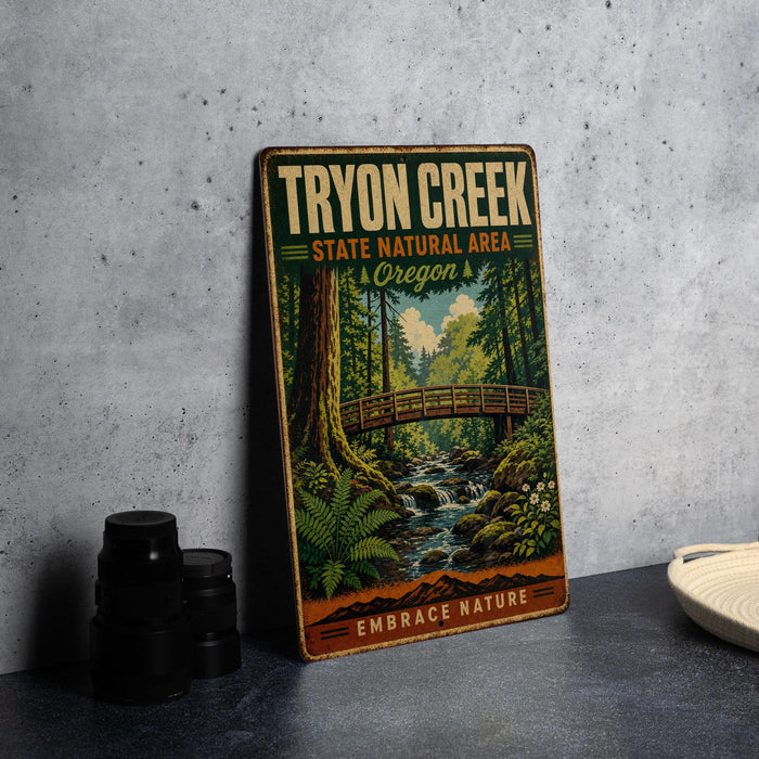 A vintage-style metal sign for the "Tryon Creek State Natural Area" in Oregon, featuring a scenic illustration of a forest and a bridge.