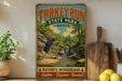 A vintage-style sign for Turkey Run State Park in Indiana, featuring a scenic landscape with a river, bridge, and lush greenery.