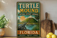 A vintage-style metal sign for the Turtle Mound National Historic Landmark in Florida, featuring a turtle on a rock and a tropical landscape.
