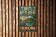 A vintage-style metal sign for Turtle Mound National Historic Landmark in Florida, featuring a turtle illustration and text promoting the preservation, protection, and honor of the landmark.