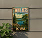 A vintage-style sign for Twin Lakes State Park in Iowa, featuring a scenic landscape with a lake, mountains, and a sailboat.