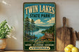 A vintage-style sign for Twin Lakes State Park, featuring a scenic landscape with pine trees, a lake, and mountains in the background.