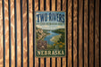A vintage-style sign for the Two Rivers State Recreation Area in Nebraska, featuring a scenic image of a river and mountains.