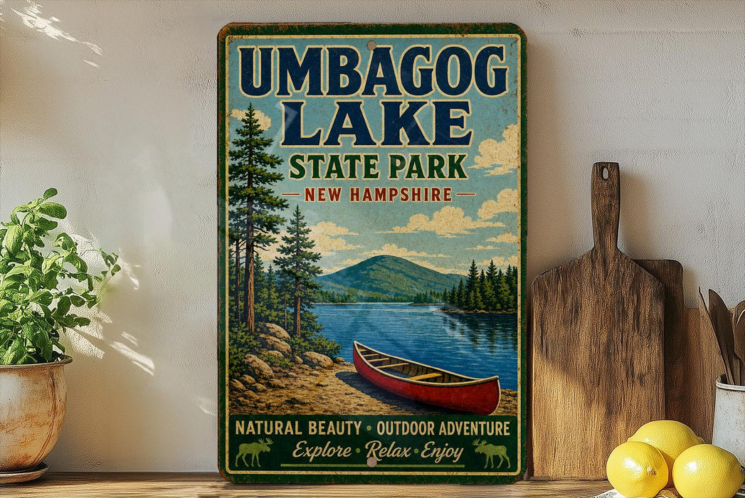 A vintage-style sign for Umbagog Lake State Park in New Hampshire, featuring a scenic image of a red canoe on a lake surrounded by pine trees and mountains.