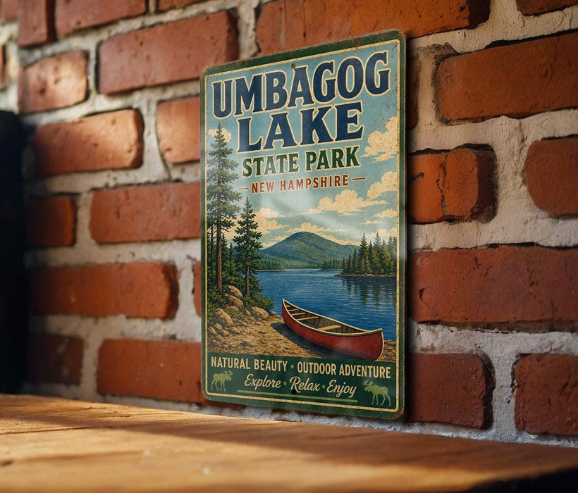 A vintage-style metal sign for Umbagog Lake, New Hampshire, featuring a scenic illustration of a lake, mountains, and a canoe.