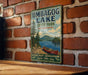 A vintage-style metal sign for Umbagog Lake, New Hampshire, featuring a scenic illustration of a lake, mountains, and a canoe.