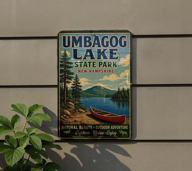 A vintage-style metal sign for Umbagog Lake State Park in New Hampshire, featuring a canoe and a scenic landscape.