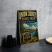 A vintage-style metal sign for Union County State Park in South Dakota, featuring a scenic landscape with a lake, mountains, and a sign inviting visitors to explore the outdoors.