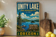 A vintage-style sign for the Unity Lake State Recreation Site in Oregon, featuring a scenic landscape with a lake, mountains, and pine trees.
