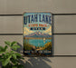A vintage-style metal sign for Utah Lake State Park, featuring a scenic landscape with mountains, a lake, and a sailboat.