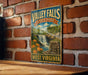 A vintage-style metal sign for Valley Falls State Park in West Virginia, featuring a scenic illustration of the waterfall and surrounding landscape.