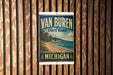 A vintage-style sign for Van Buren State Park in Michigan, featuring a scenic landscape with a beach, mountains, and a lake.