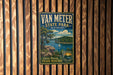 A vintage metal sign for Van Meter State Park in Missouri, featuring a scenic landscape with a lake, mountains, and a sailboat.