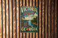 A vintage-style metal sign for Victoria, Georgia, featuring a scenic landscape with a lake, trees, and mountains.