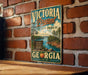 A vintage-style metal sign for Victoria Bryant State Park in Georgia, featuring a scenic landscape with a lake, mountains, and a picnic area.