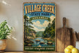a vintage-style sign for "Village Creek State Park" in Arkansas, with a scenic illustration of a river, trees, and mountains. The sign is displayed on a wooden shelf, surrounded by various kitchen utensils and a potted plant.