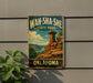 A vintage-style metal sign for Wah-Sha-She State Park in Oklahoma, featuring a scenic landscape with a rock formation and a body of water.