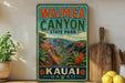 A vintage-style metal sign for Waimea Canyon State Park in Kauai, Hawaii, featuring a scenic mountain landscape with palm trees and flowers.
