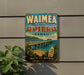 A vintage-style sign for Waimea Pier in Hawaii, featuring a scenic image of the pier and the ocean.