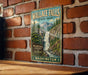 A vintage metal sign for Wallace Falls State Park in Washington, featuring a scenic illustration of the waterfall surrounded by pine trees and mountains.