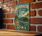 A vintage-style metal sign for Wapsipicon State Park in Iowa, featuring a scenic landscape with a river and bridge.