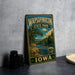 A vintage-style metal sign for Wapsipinicon State Park in Iowa, featuring a scenic illustration of a river and forest landscape.