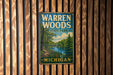 A vintage metal sign for Warren Woods State Park in Michigan, featuring a scenic illustration of a forest and a river.