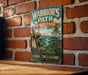 A vintage-style metal sign for "Warrior's Path" in Tennessee, featuring a scenic mountain landscape with a river and pine trees.