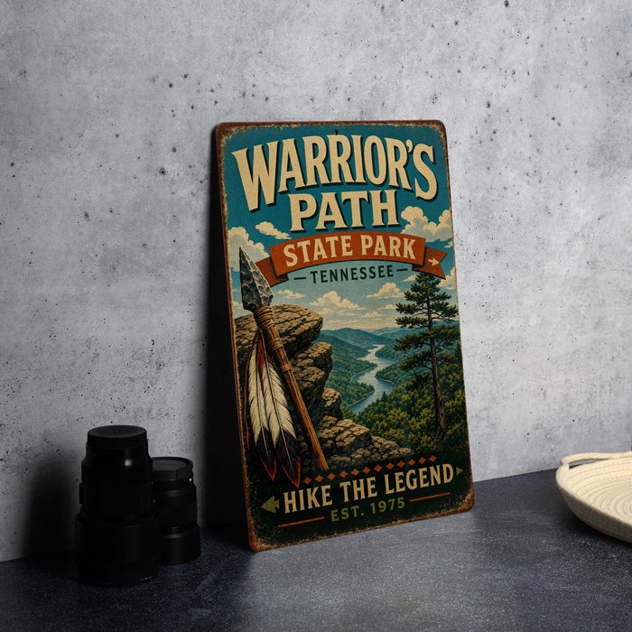 A vintage-style metal sign for Warrior's Path State Park in Tennessee, featuring a scenic mountain landscape with a Native American headdress and the text "HIKE THE LEGEND EST. 1975".