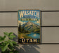 A vintage-style metal sign for Wasatch Mountain State Park in Utah, featuring a scenic mountain landscape with pine trees and a lake.
