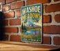 A vintage-style metal sign for Washoe Meadows State Park in California, featuring a scenic landscape with mountains, a lake, and wildflowers.