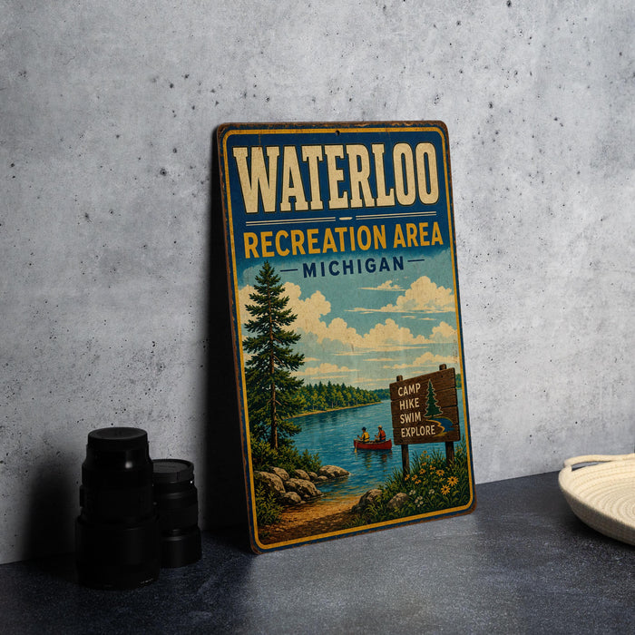 A vintage metal sign for the Waterloo Recreation Area in Michigan, featuring a scenic illustration of a lake, pine trees, and a camp sign.