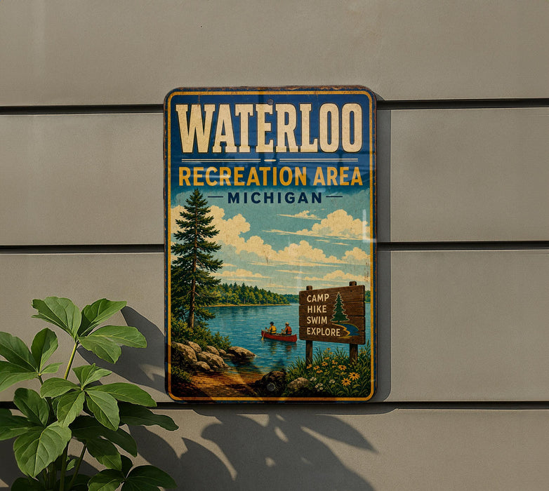 A vintage-style metal sign for the Waterloo Recreation Area in Michigan, featuring a scenic landscape with a lake, pine trees, and a sign indicating the location of a camp, hike, swim, and explore area.