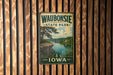 A vintage metal sign for Waubonsie State Park in Iowa, featuring a scenic landscape with a river and a cliff.