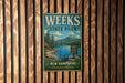 A vintage metal sign for Weeks State Park, featuring a scenic landscape with a lake, mountains, and pine trees, mounted on a wooden wall.